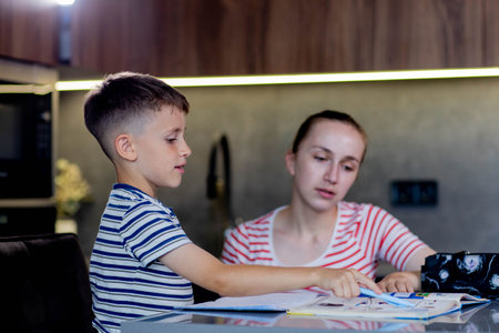 Mother helping her son doing homework in kitchenの写真素材