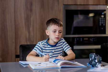 Boy is doing his homework in the kitchenの写真素材