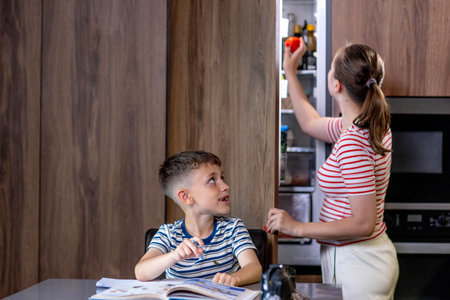 Beautiful mother helping son doing schoolwork at homeの写真素材