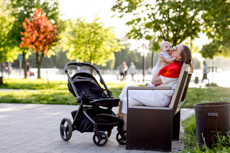 Young mother with her cute baby is sitting on a park benchの写真素材