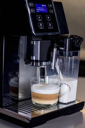 Modern coffee machine with glass cup of latte in kitchenの写真素材