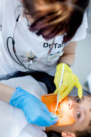 Dentist treats the childs tooth using a rubber dam.の写真素材