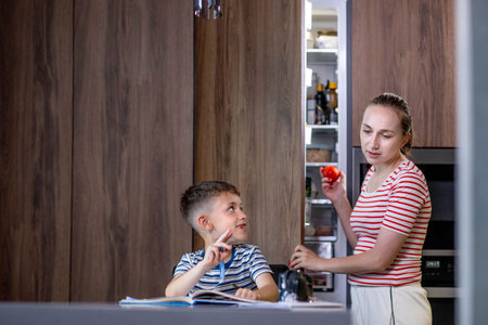 Beautiful mother helping son doing schoolwork at home.の写真素材