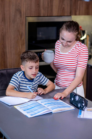Mother helping son with homework in kitchen at home.の写真素材