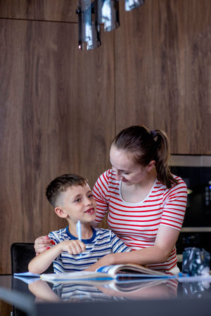 Mother helping her son doing homework in kitchen.の写真素材