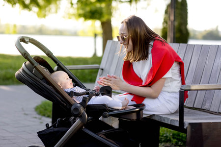 Young mother with her cute baby is sitting on a park bench.の写真素材