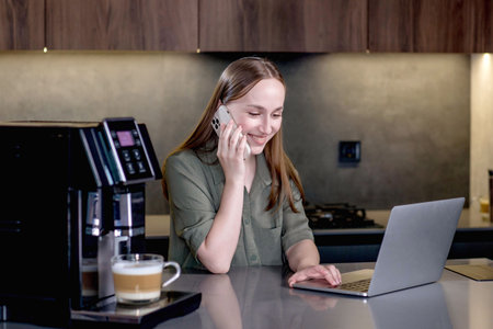 Coffee machine prepares coffee while the woman working at the computer and talking on the phone.の写真素材