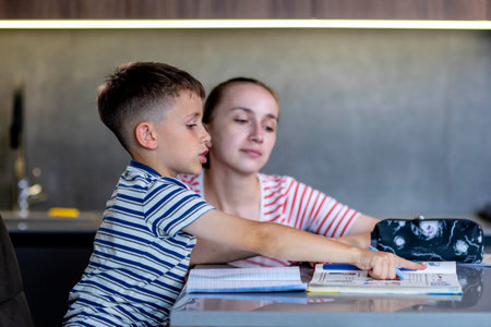 Mother helping her son doing homework in kitchen.の写真素材