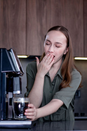 Sleepy woman making coffee at home.の写真素材