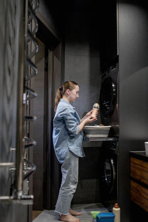 Young woman holds a conditioner in granules for clothes in the bathroomの写真素材