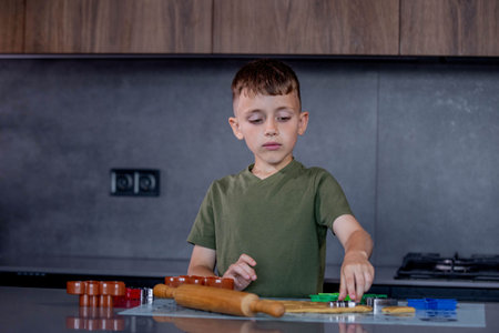 Little boy making cookies using cookie cutters and dough in the kitchen at home.の写真素材