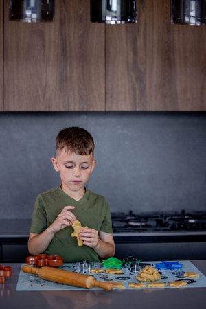 Little boy making cookies using cookie cutters and dough in the kitchen at home.の写真素材