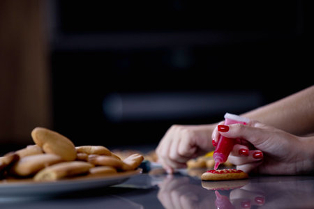 Cute boy decorating gingerbread cookies at home kitchen.の写真素材