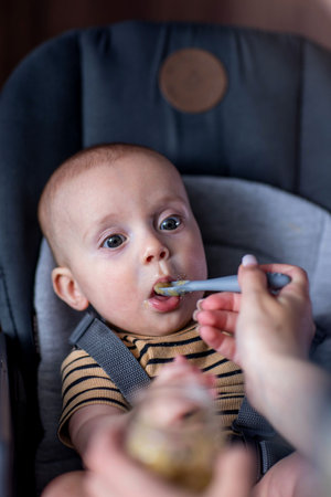 Cute baby is enjoying his first meal at home with his mom.の写真素材