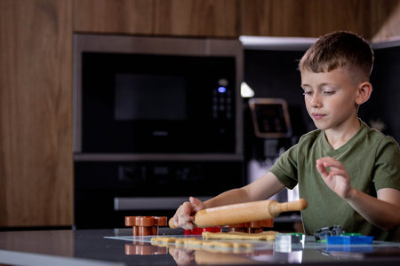 Little boy rolling out gingerbread dough on the table with a rolling pinの写真素材