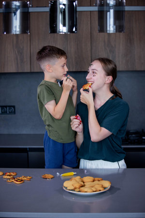 Mother and her son eating freshly baked gingerbread together.の写真素材