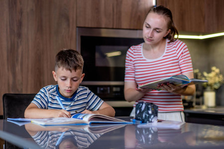 Mother helping son with homework in kitchen at home.の写真素材