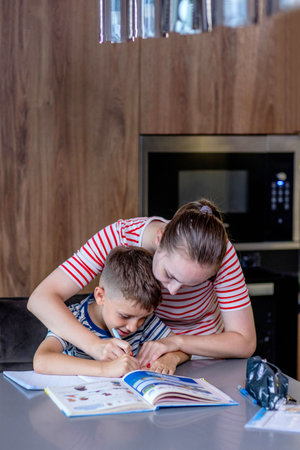 Mother helping her son doing homework in kitchen.の写真素材