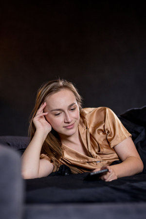 Woman with smartphone and relaxing on sofa in living room.の写真素材