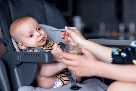 Cute baby is enjoying his first meal at home with his mom.の写真素材
