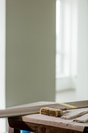 On the surface of a wooden table, there sits a brush alongside a piece of wood, creating a scene of craftsmanship and artistryの写真素材