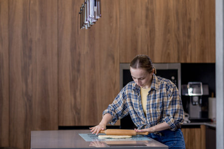 Woman skillfully rolls out dough, perfectly showing her culinary expertise in a kitchen.の写真素材