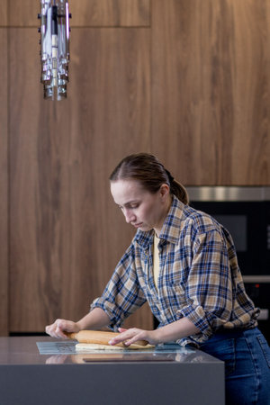 Woman skillfully rolls out dough, perfectly showing her culinary expertise in a kitchen.の写真素材