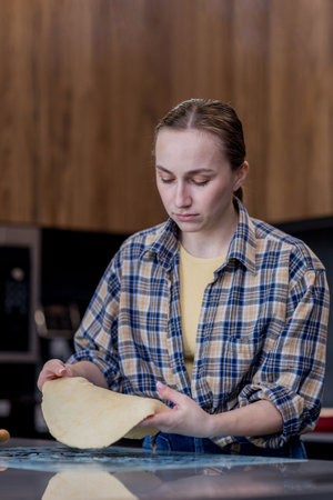 Woman skillfully rolls out dough, perfectly showing her culinary expertise in a kitchen.の写真素材