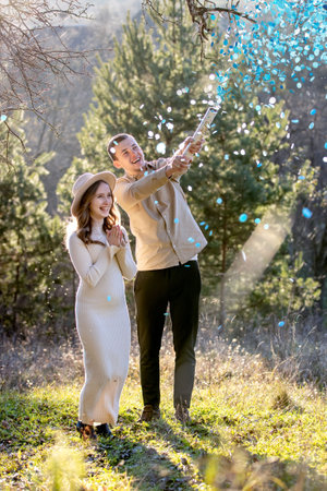 Happy couple happily celebrating their pregnancy surrounded by blue confetti.の写真素材
