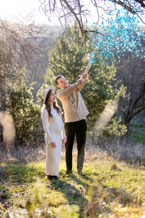 Happy couple happily celebrating their pregnancy surrounded by blue confetti.の写真素材