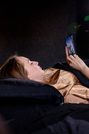 Attractive woman with smartphone and relaxing on sofa in living room.の写真素材