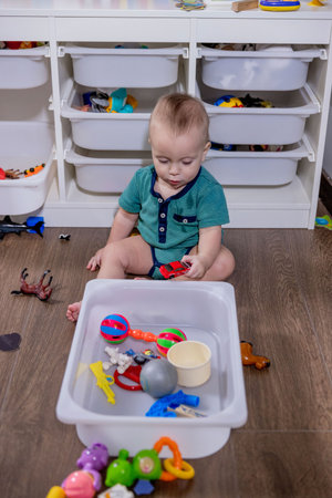 A young baby is happily playing with colorful toys that are kept inside a clean white bin, enjoying their exploration and interactionの写真素材