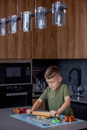 Little boy rolling out gingerbread dough on the table with a rolling pinの写真素材