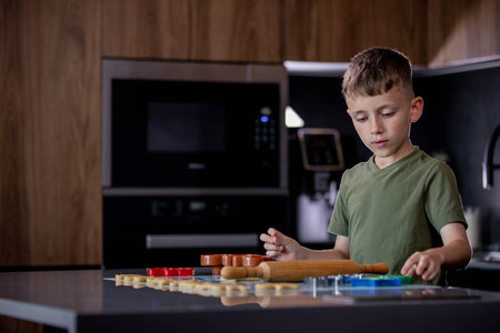 Little boy rolling out gingerbread dough on the table with a rolling pinの写真素材