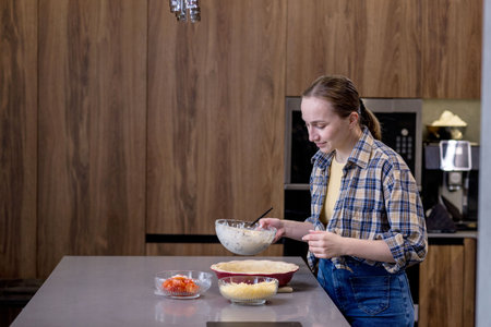 Young woman preparing quiche in the kitchen.の写真素材