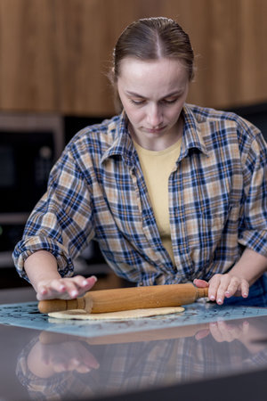 Woman skillfully rolls out dough, perfectly showing her culinary expertise in a kitchen.の写真素材