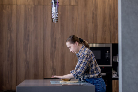 Woman skillfully rolls out dough, perfectly showing her culinary expertise in a kitchen.の写真素材