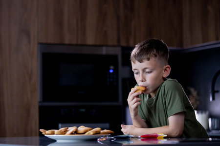 A Thoughtful Young Boy Enjoying Delicious Cookies in a Modern and Cozy Kitchen Environment.の写真素材