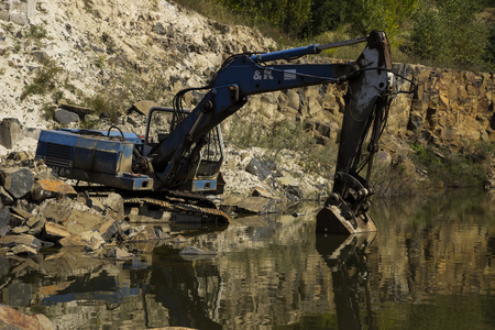 Broken excavator and basalt columns rocks. Heavy industry. Stone excavation. Producing stone from basalt pillars.の写真素材