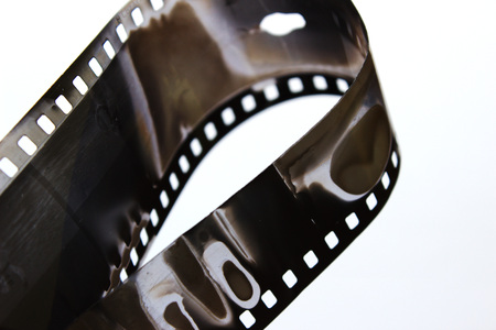 Old black and white film in a spiral over white background. Very old black and white film.の写真素材