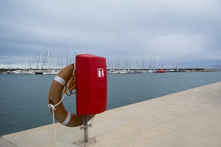 Lifebuoy in the marina for yachts. Red circle on the boat dock. uxury Yachts And Boats In Valencia Port At Mediterranean Sea. White yachts are in the Spanish port of Valenciaの写真素材