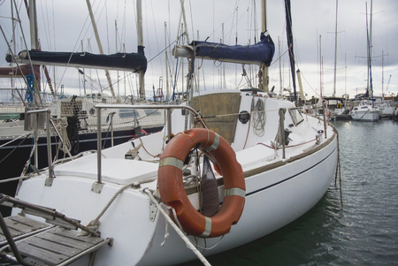 Boat In Valencia Port At Mediterranean Sea. Reflexion in the water. White yacht are in the Spanish port of Valencia in the beginning of spring. Cloudy sky.の写真素材
