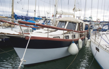 Boat In Valencia Port At Mediterranean Sea. Reflexion in the water. White yacht are in the Spanish port of Valencia in the beginning of spring. Cloudy sky.の写真素材
