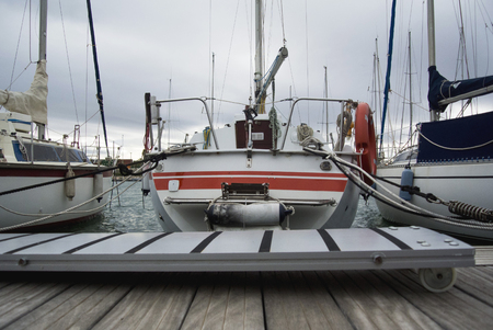 Boat In Valencia Port At Mediterranean Sea. Reflexion in the water. White yacht are in the Spanish port of Valencia in the beginning of spring. Cloudy sky.の写真素材