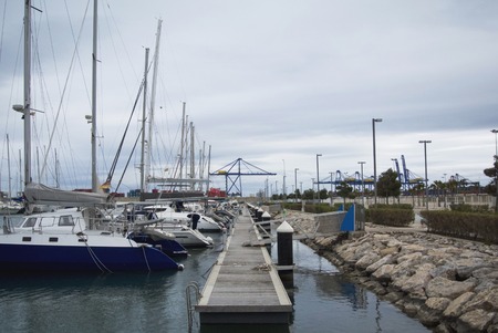 Luxury Yachts And Boats In Valencia Port At Mediterranean Sea. Reflexion in the water. White yachts are in the Spanish port of Valencia in the beginning of spring. Cloudy sky.の写真素材