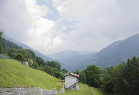 Panoramic view of idyllic alpine mountain scenery with italian house and fresh green meadows in beautiful cloudy weather in summer, Italyの写真素材