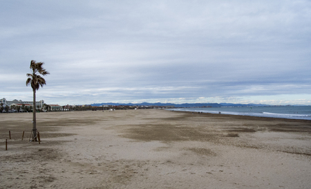 Cloudy beach with waves of the sea. Empty spring beach of mediterranean sea in Valencia, Spainの写真素材
