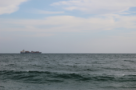 Cargo vessel in the stormy sea under the cloudy skiesの写真素材