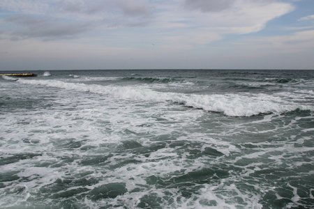 Cloudy weather. Golden sand, waves and foam. Cloudy day on the sandy beach. Panoramic view of beautiful sandy beach. Beach and waves with gloomy skyの写真素材