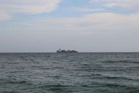 Cargo vessel in the stormy sea under the cloudy skiesの写真素材